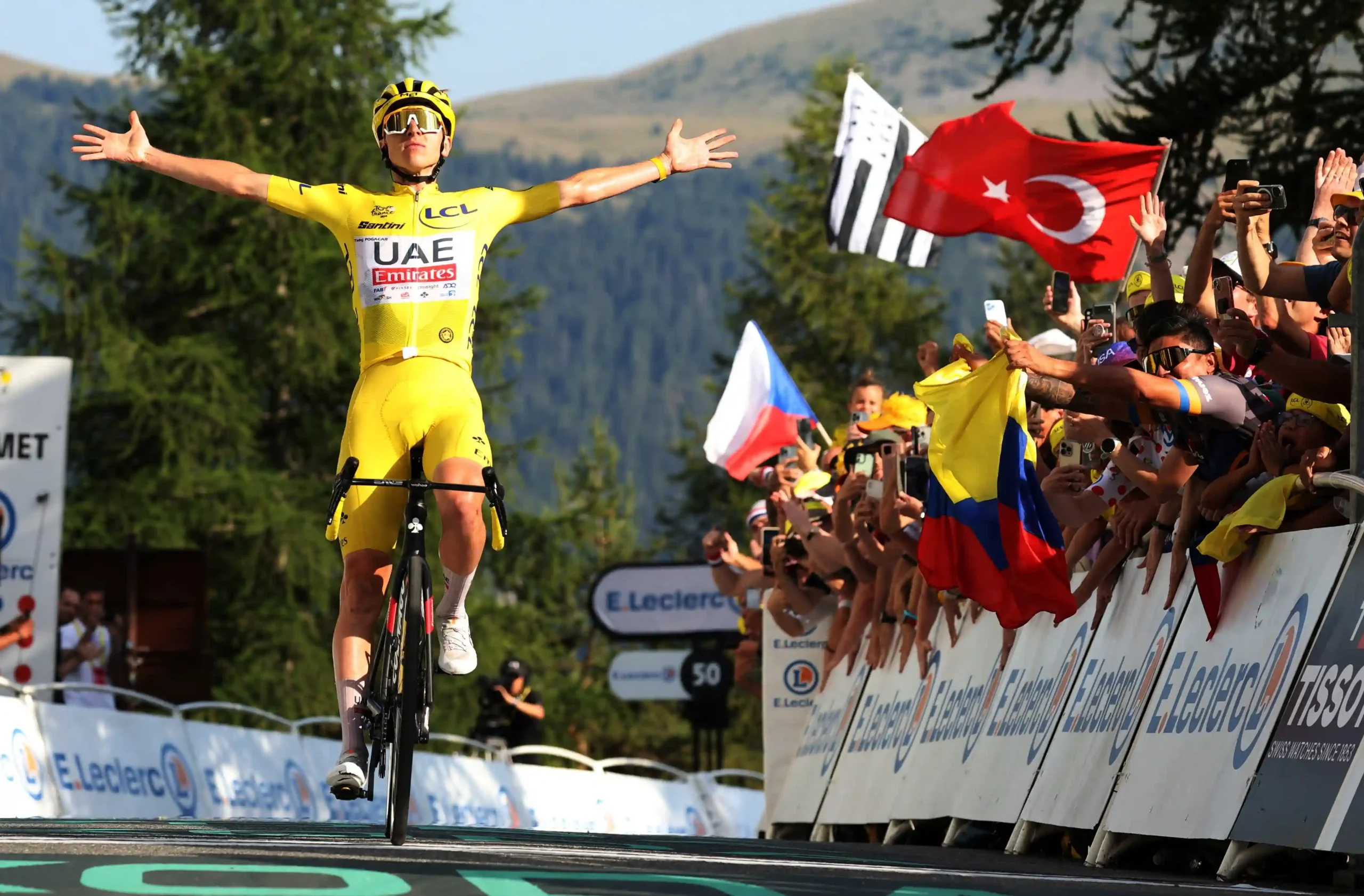 The Tour de France peloton cycling through a scenic mountain pass.
