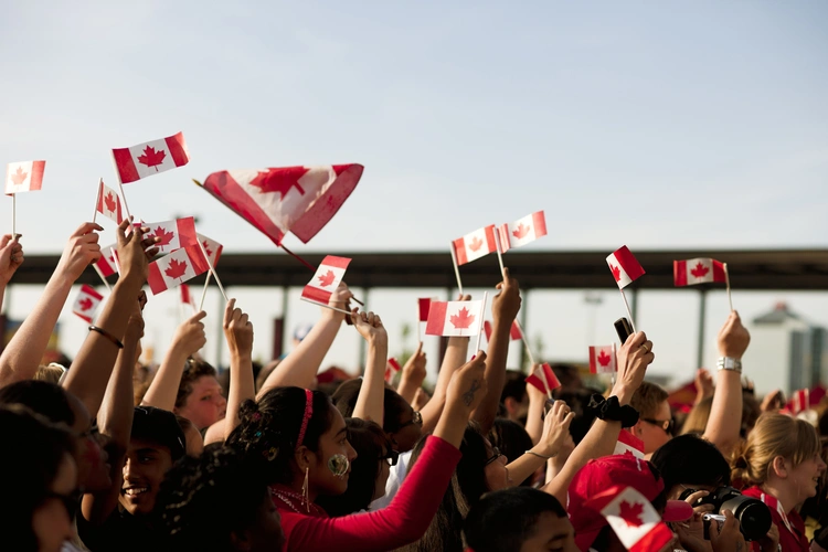 A crowd celebrating with Canadian flags during Canada Day fireworks
