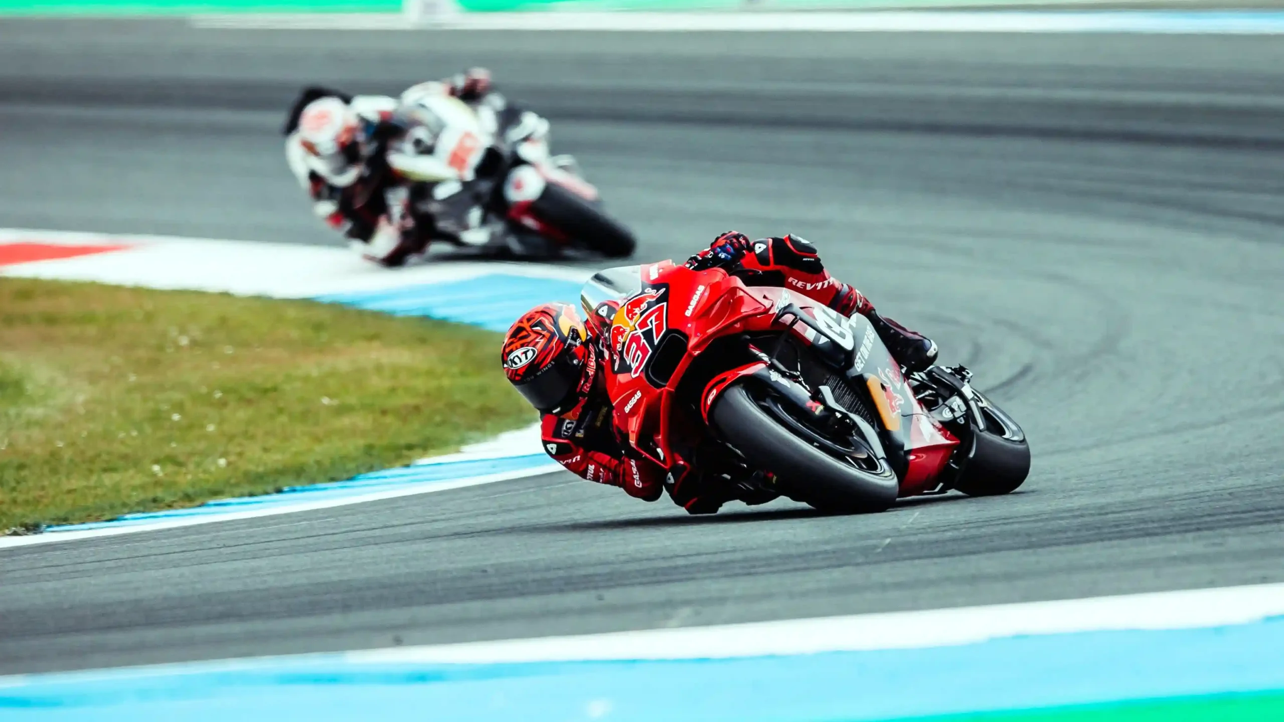 MotoGP motorcycles leaning into a fast corner at the TT Circuit Assen