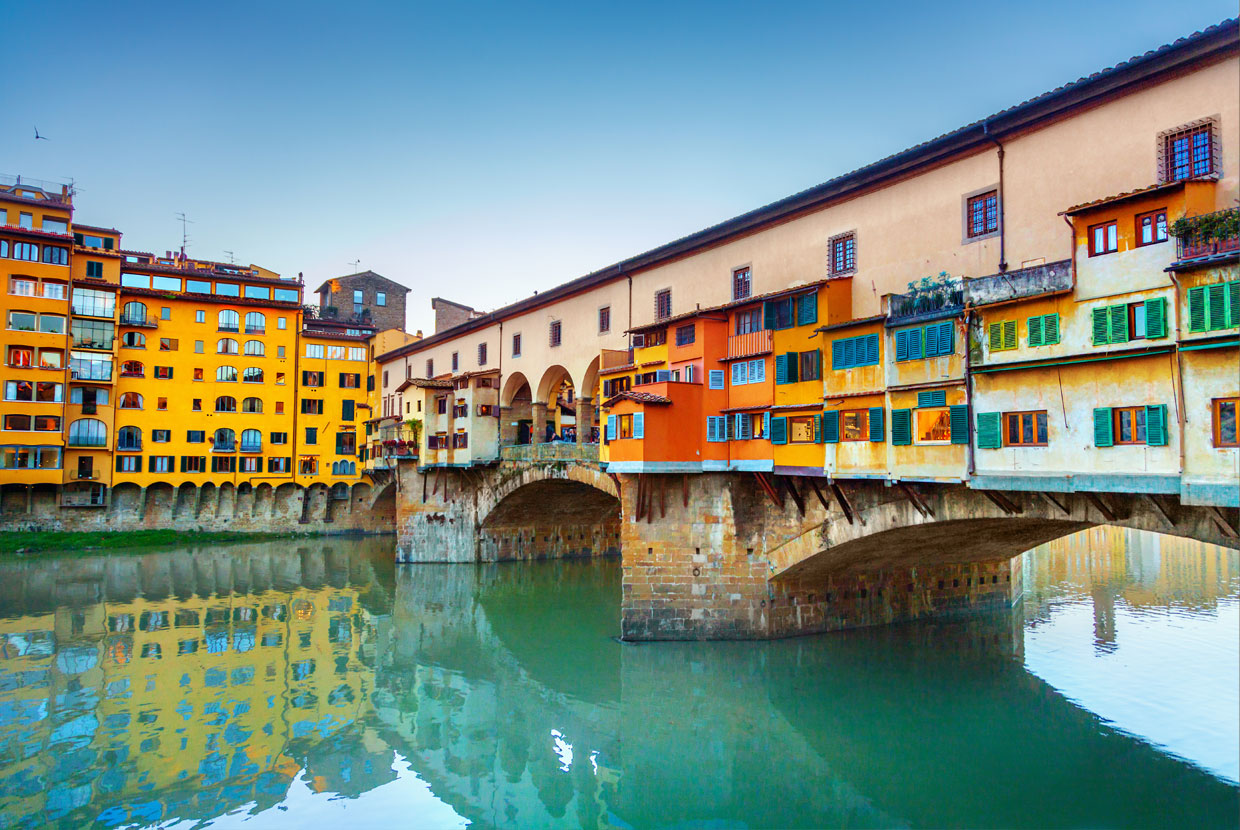 Ponte Vecchio bridge over the Arno River in Florence at sunset.
